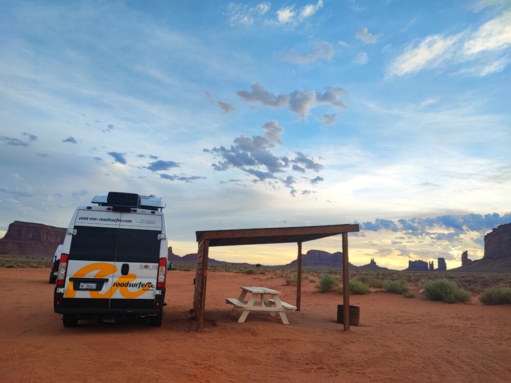 Nuestra camper de alquiler de Roadsurfer acampada delante de Monument Valley durante un amanecer espectacular