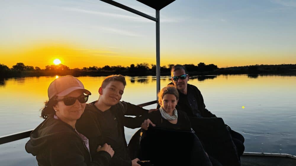 Familia disfrutando del atardecer durante un tour en barco por el río Okavango en Caprivi Namibia